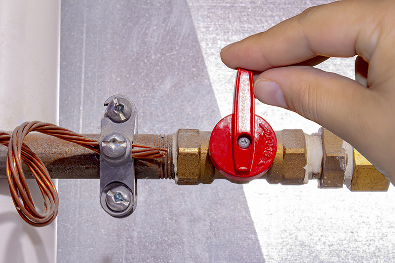 A person turning on off a natural gas red tap.