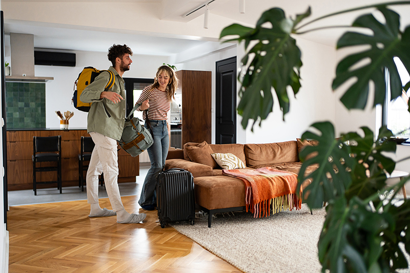 Young couple arriving at their vacation stay with luggage and smiling